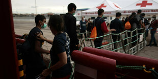 Migranten gehen im Hafen von Taranto (Italien) an Land.