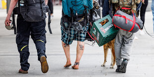 Die Beine von drei Punks mit Rucksack und Bierkiste