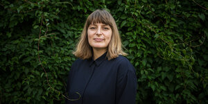 Portrait von Sarah Bäcker vor einer grünen Hecke