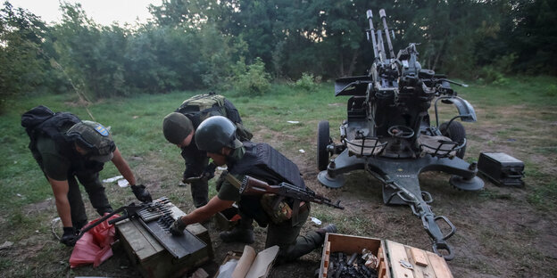 Ukrainian soldiers load shells next to an anti-aircraft gun