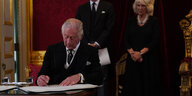 König Charles III. unterschreibt im Beisein seines Sohnes, William, Prinz von Wales, und seiner Gemahlin, Königin Camilla, einen Eid