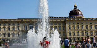 Ein Kind spielt vor dem Berliner Stadtschloss in einer Wasserfontäne