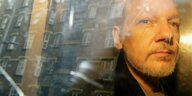 Julian Assange, durch die Scheibe eines Autos fotografiert, in dem sie eine Häuserzeile spiegelt