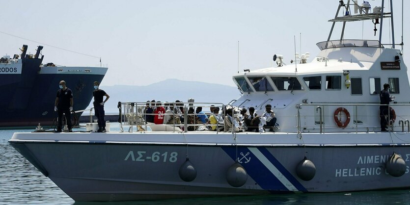 An Deck eines Schiffes auf dem Meer stehen Menschen