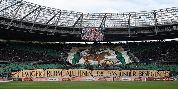 Fußballfans von Hannover 96 zeigen vor Spielbeginn ein Banner, auf dem unter dem Titel "Königreich 96 Hannover" das Pferd eines Reiters einen Löwen zertritt, auf einem weiteren Banner darunter ist zu lesen "Ewiger Ruhm all jenen, die das Untier besiegen