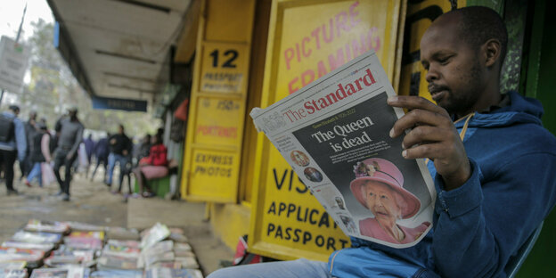 Ein Mann in Nairobi sitzt vor seinem Laden und liest die Zeitung mit der Titelgeschichte über den Tod der Queen