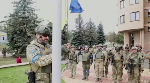 A soldier hoists the Ukrainian flag