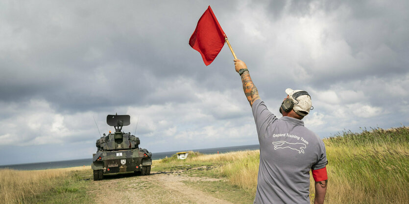 Mann mit roter Flagge steht bei einer Schießübung in Schleswig-Holstein einem Panzer vom Typ Gepard gegenüber. Dieser wurde bereits an die Ukraine geliefert