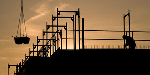 Bauarbeiter bauen bei Sonnenaufgang an einem Wohnhaus.