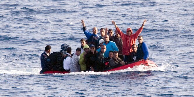 Ein kleines Boot mit vielen Männern an Bord, von denen einige die Arme in die Luft recken