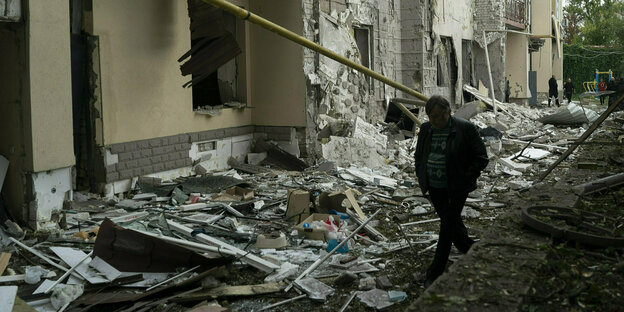 Ein Bewohner Kharkivs geht an bescchädigten Häusern vorbei