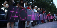 Menschen halten leuchtende Schilder, die zusammen „#CHRISTIAN TAYLOR“ ergeben