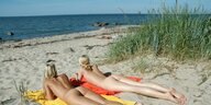 zwei nackte Frauen in Bauchlage am Strand
