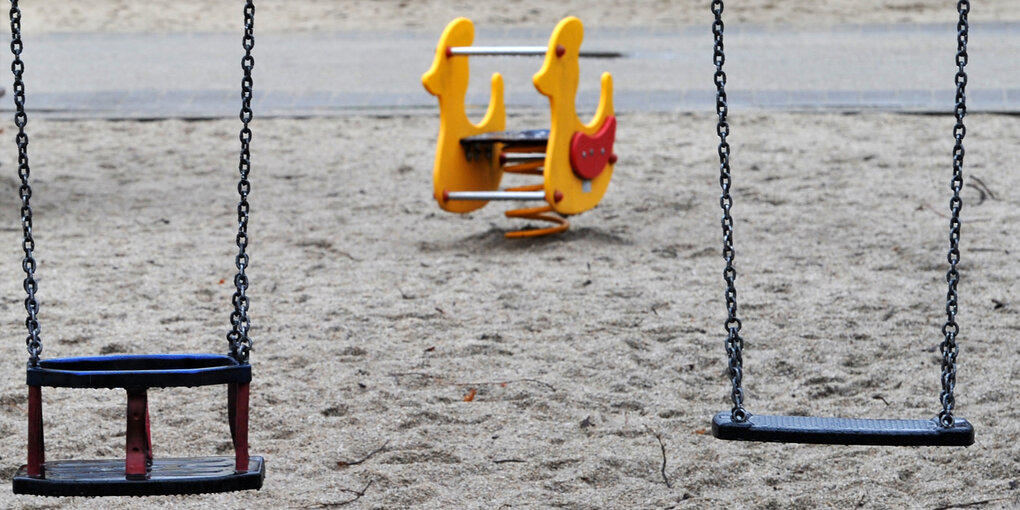 Zwei nicht besetzte Schaukeln auf einem Spielplatz