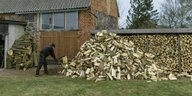 Ein Mann hat jede Menge Holz gehackt und vor einem kleinen Haus gestapelt