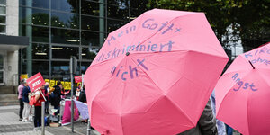 Pinke Regenschirme mit Protest beschriftet