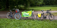 Drei Fahrräder stehen in einem Park - über das Fahrrad in der Mitte hängt ein Banner der Partei: Bündnis90 Die Grünen