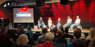 Fünf Personen sitzen vor Publikum auf einer Bühne beim taz klimaland Talk in Freiburg