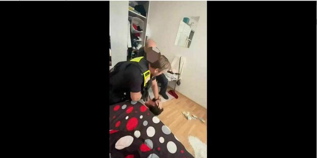 Zwei Polizisten drücken einen Mann zu Boden