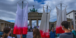 Drei Frauen protestieren mit blutigen Kleidern gegen den "Marsch für das Leben" von Abtreibungsgegner*innen.