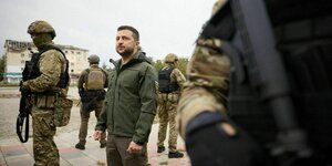 Der ukrainische Präsident steht in khakifarbener Kleidung in Isjum auf einem Platz, umgeben von bewaffeneten Soldaten