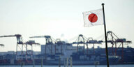 Eine japanische Nationalflagge weht in der Nähe eines Containerhafens