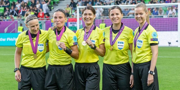 Fünf Fußballschiedsrichterinnen, die je eine Medaille um ihren Hals tragen