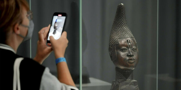 Eine Frau fotogafiert eine der berühmten Benin-Bronzen in einer Vitrine