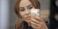 Eine Frau mit Botox-Lippen und gelifteter Haut macht ein Spiegel-Selfie.