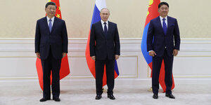 Drei Männer stehen vor den Fahnen ihrere jeweiligen Länder