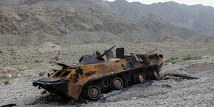Ein ausgebrannter Panzer steht vor einer steinigen Landschaft