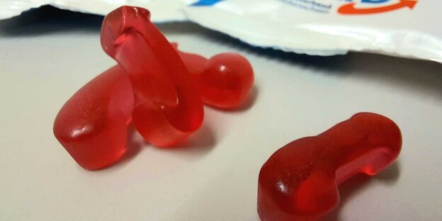 Red gummy bears in the form of arrows lie on a table