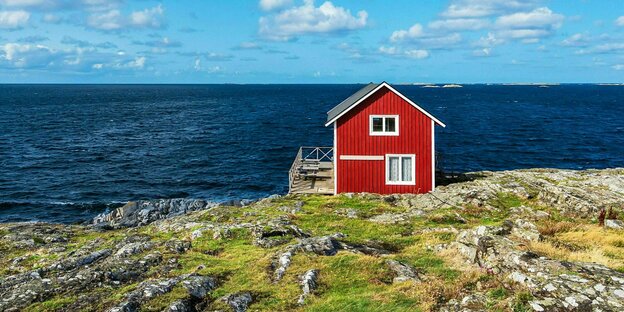 A red wooden house stands on a bay