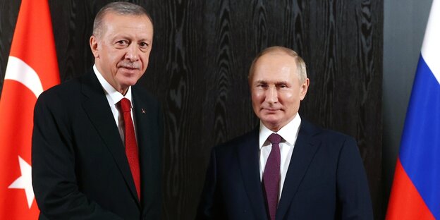 Erdogan und Putin schütteln sie die Hand vor den Landesflaggen der Türkei und Russlands