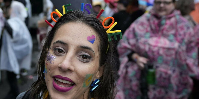 Europride-Teilnehmer*in mit Schriftzug: Love is love im Haar