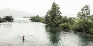 Ein einzelner Angler steht in einem Fluss