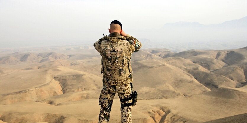 Ein Bundeswehrsoldat blickt über eine bergige landschaft