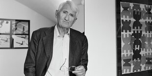 Habermas lehnt an einem Pfosten in Jacket und offenem Hemd