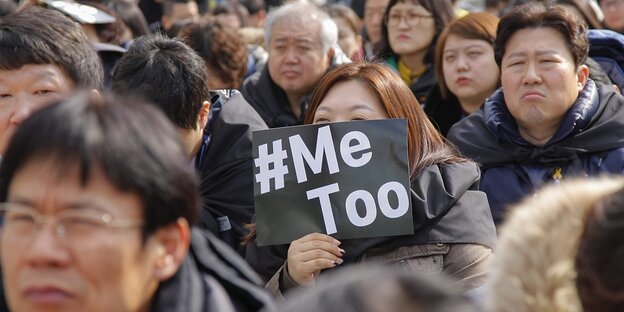 Eine Menschenmenge, eine Frau hält ein Schild auf dem "Me too" zu lesen ist