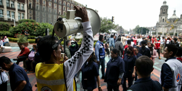 Ein Mann mit Megafon spricht beim Beben zu auf dem Zócalo-Platz versammelten Menschen.