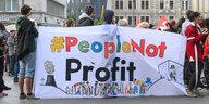 Menschen stehen mit einem Banner mit der Aufschrift People not Profit auf dem Marktplatz in Halle
