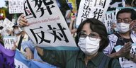 Menschen protestieren mit Schildern auf denen japanische Schriftzeichen zu sehen sind