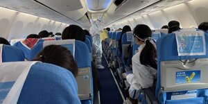Innenraum eines chinesischen Flugzeugs mit einer Stewardess im Seuchenschutzanzug