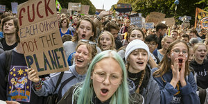 Eine große Masse rufender Schüler*innen, eine von ihnen hält ein Schild, auf dem steht 