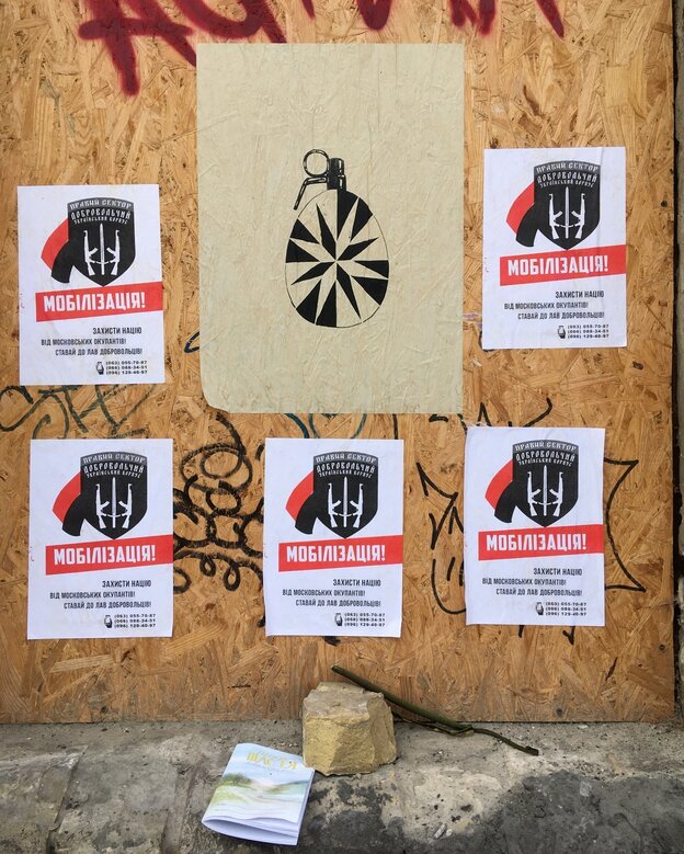 Plakate auf eienr Holzwand rufen auf, sich freiwillig zum Militär zu melden