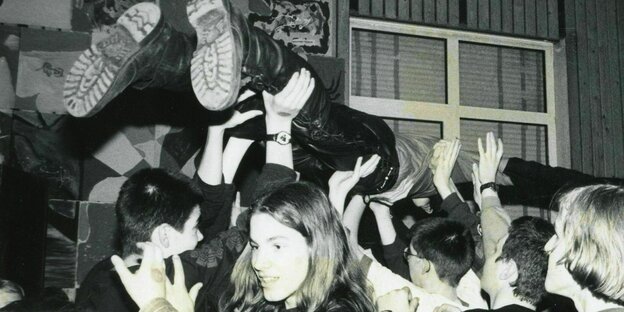 Eine feiernde Menge trägt eine Person auf ihren Händen durch die Luft - bei einem Konzert im Jugendhaus Neumünster in der 1980er Jahren