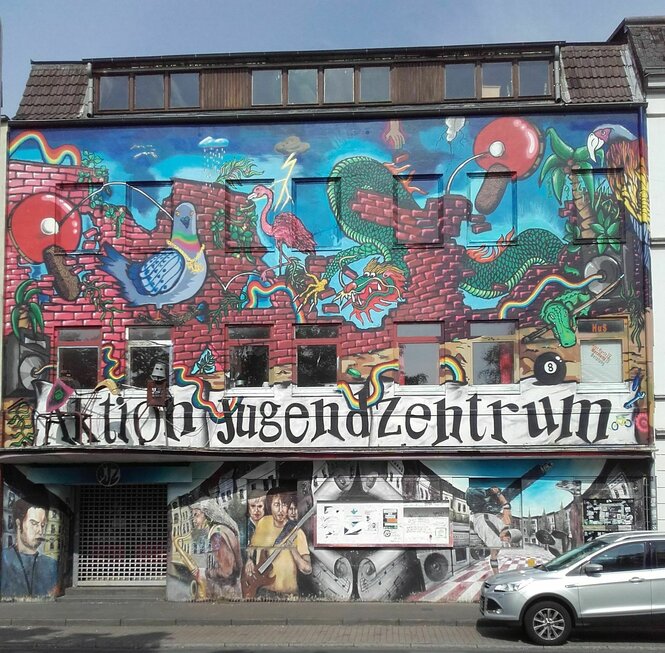 Eine kunterbunte Außen­fassade des AJZ Neumünster, gestaltet nach Ideen der der dort aktiven Kinder