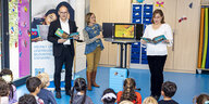 Der niedersächsische Kultusminister Grant Hendrick Tonne steht vor Grundschülern und liest vor.
