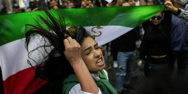 Eine Frau protestiert mit wehenden Haaren vor einer iranischen Fahne während einer Demonstration vor der iranischen Botschaft in Istanbul