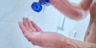 Hände mit Shampooflasche unter Dusche